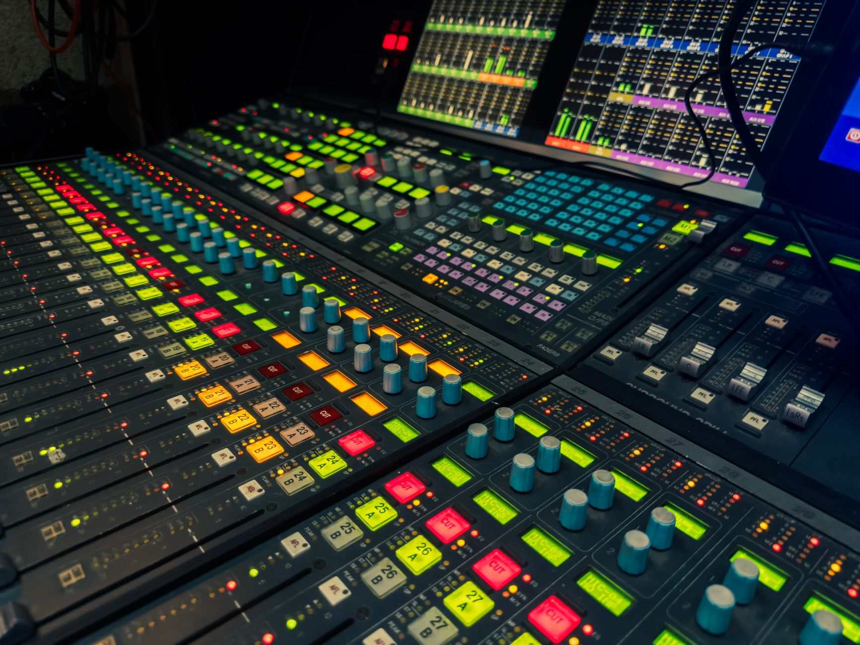 An array of colorful controls on a professional audio mixing console in a studio setting.
