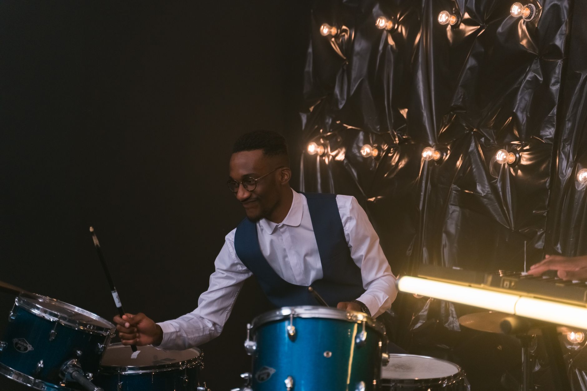 A talented drummer performing passionately in an indoor studio with ambient lighting.